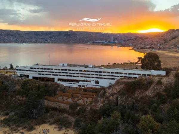 Luxury Hotels in Puno: panoramic sunset view of a lakefront hotel on Lake Titicaca with Puno city in the background.