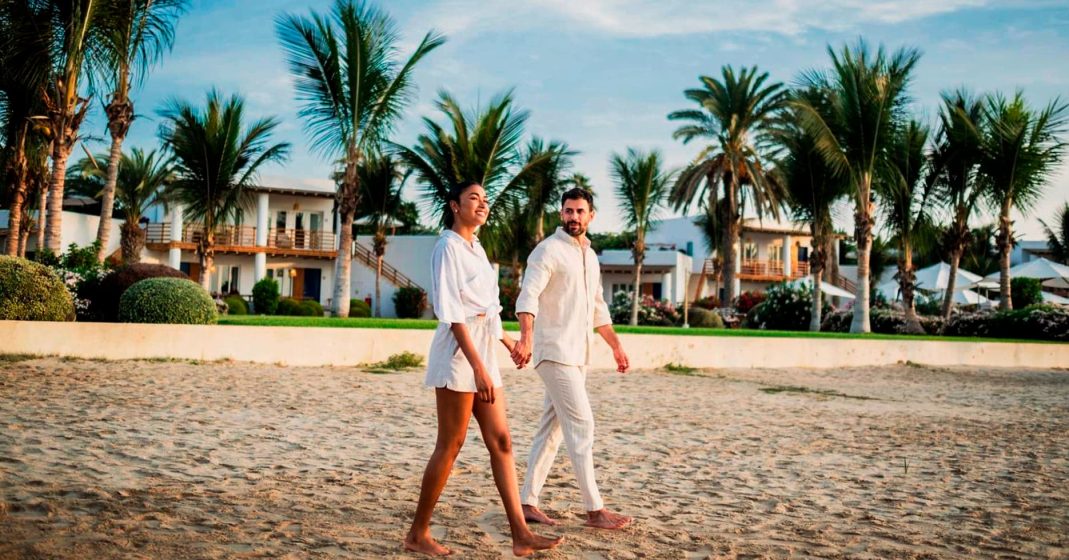 Tourists at the Paracas resorts, walking on the sand and overlooking palm trees