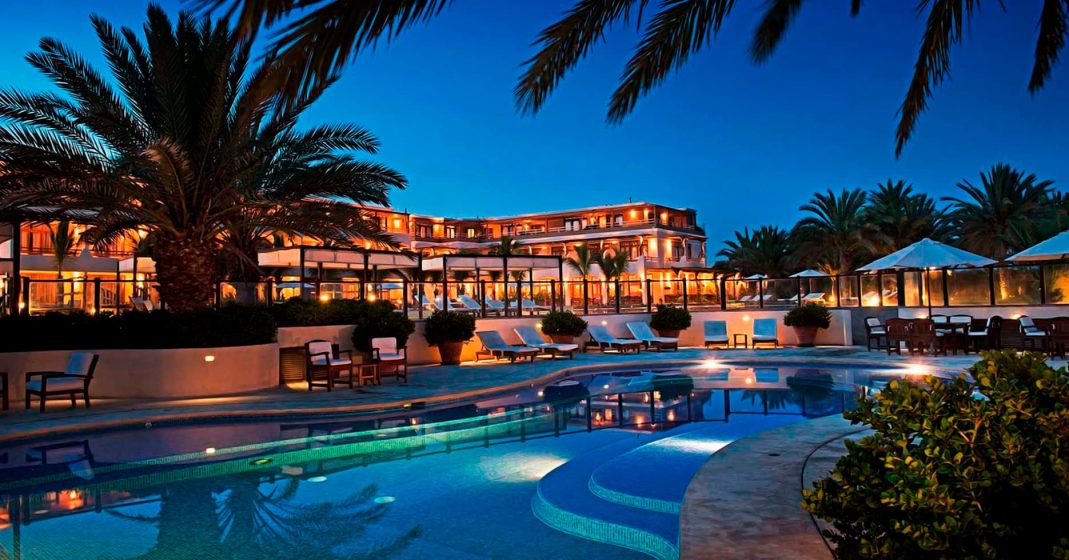 Luxury Hotel Paracas, La Hacienda Bahia Paracas, with a view of the pool, lounge chairs, and palm trees.