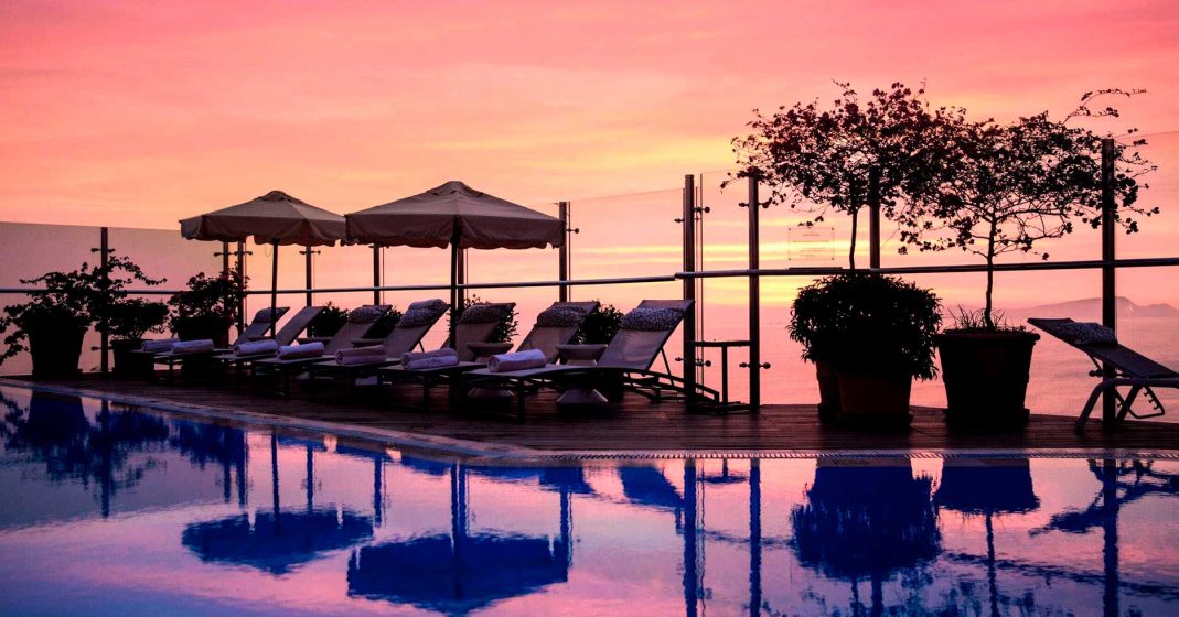 Luxury hotels in Lima, Peru - Miraflores Park Belmond rooftop view, pool, lounge chairs in front of the pool, and a sunset