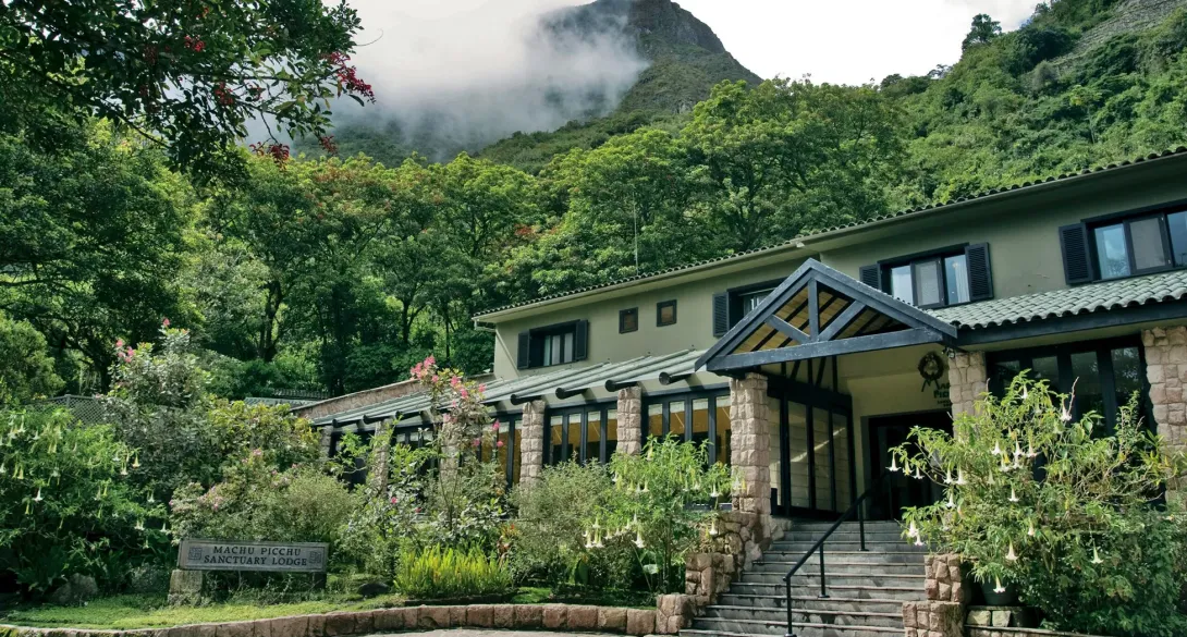 Belmond Sanctuary Lodge luxury hotel at the entrance of Machu Picchu, surrounded by lush mountains and cloud forest greenery.
