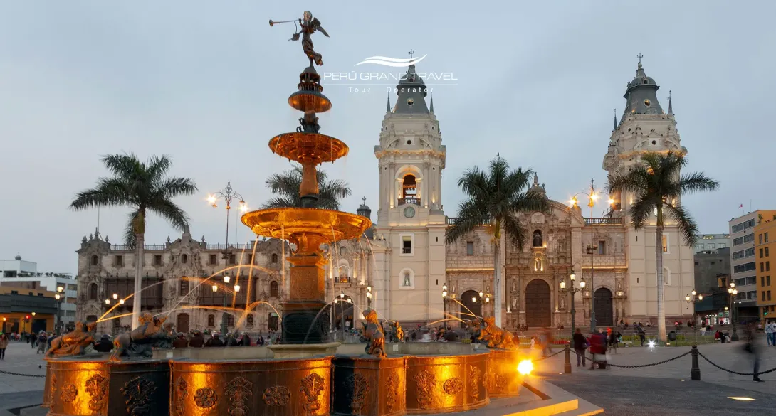 Things to Do in Lima Peru: Illuminated fountain in Lima’s Plaza Mayor at dusk, with the Lima Cathedral and palm trees in the Historic Center in the background.